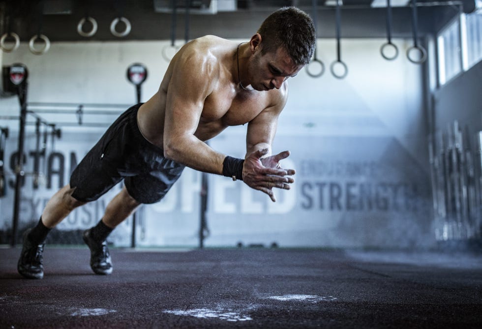 young athletic man exercising push ups while clapping his hands in a gym