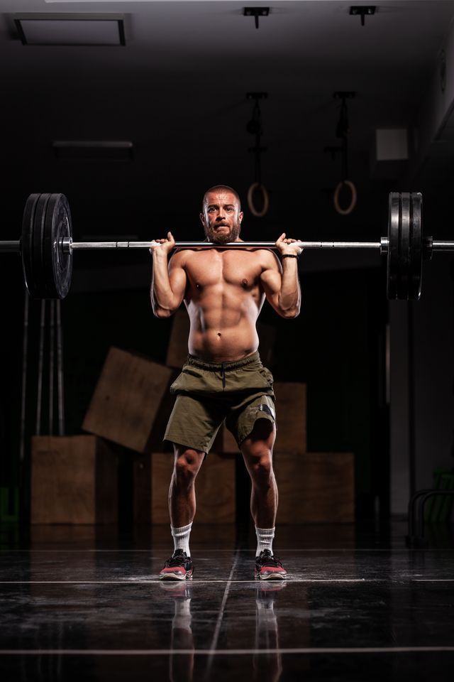 muscular athlete lifting very heavy barbell