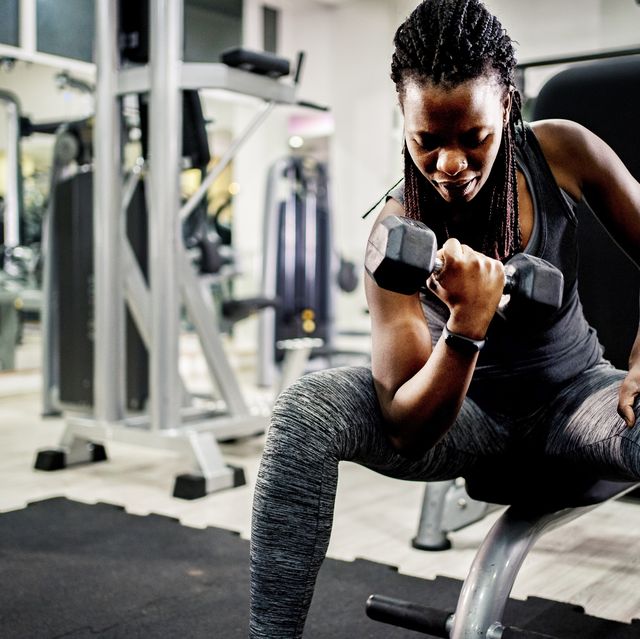 muscular black girl in sportswear lifting dumbbell