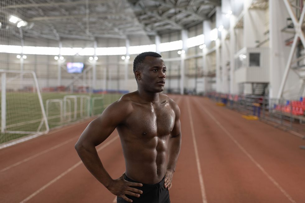 muscular black runner resting on track
