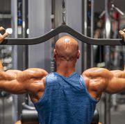 muscular bodybuilder using lat pulldown machine in gym