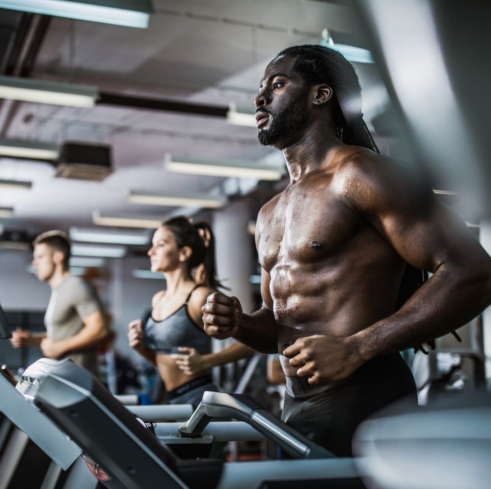 muscular man warming up on treadmill in a health club