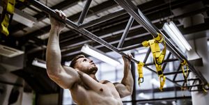 Muscular build man exercising chin-ups in a gym.