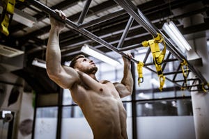 Muscular build man exercising chin-ups in a gym.