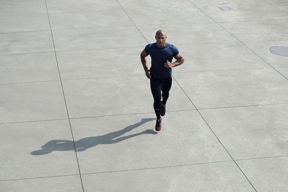 muscular build man running outdoors on concrete surface