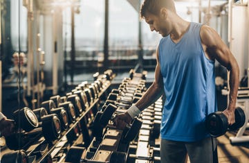 Muscular build sportsman taking weights from a rack in a gym.