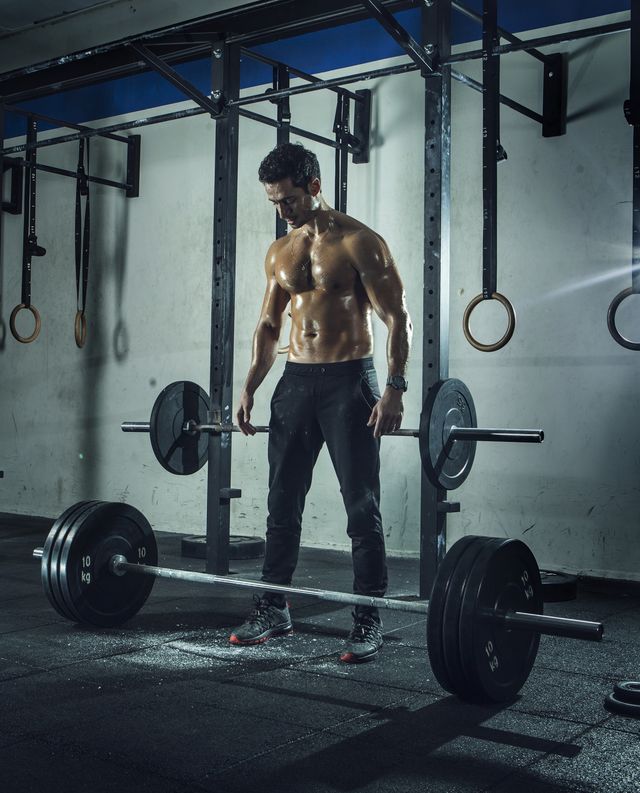 muscular built man preparing to lift barbell