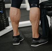 muscular calves legs of young activy athlete male wearing sneakers in sport gym