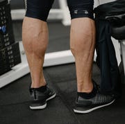 muscular calves legs of young activy athlete male wearing sneakers in sport gym