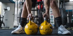 muscular male athlete holding kettlebells in gym