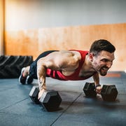 muscular man doing pushup exercise with dumbbell