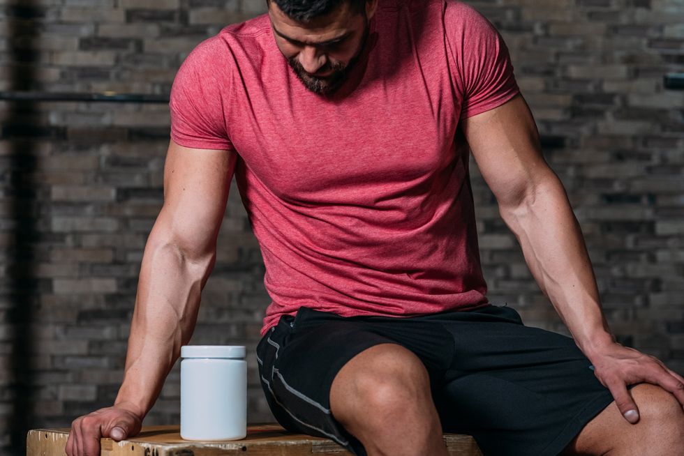 muscular man holding sport nutrition product