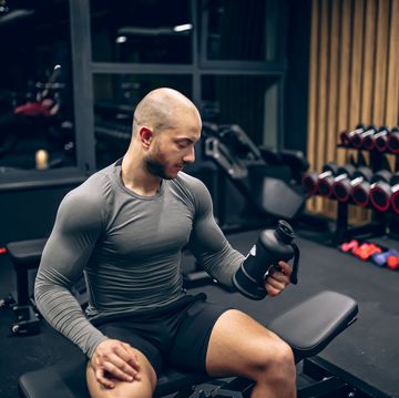 muscular man shaking his supplement shaker in gym