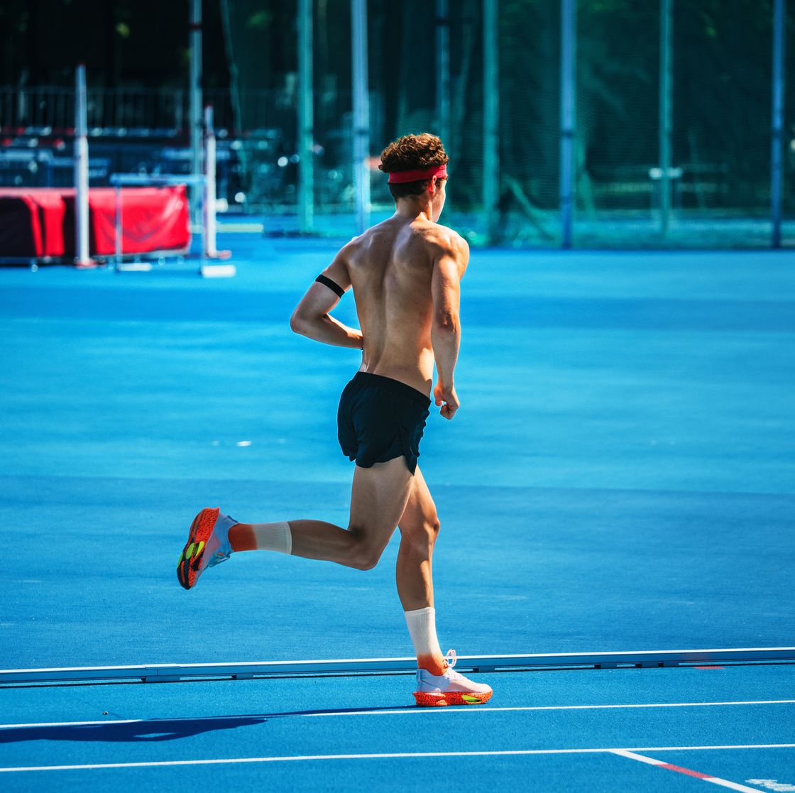 muscular pentathlete running on blue stadium during laser run team training for international level competition, sunny day