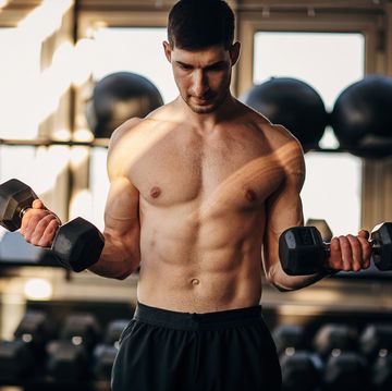 muscular shirtless man exercising with dumbbells