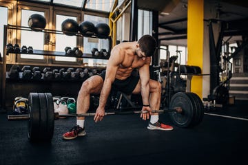 muscular shirtless man exercising with weights in gym