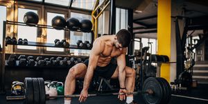muscular shirtless man exercising with weights in gym