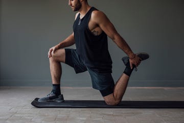 muscular sportsman stretching his legs to warm up for a workout