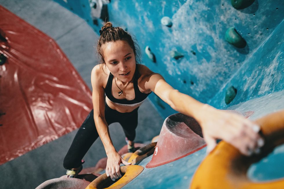 muscular woman on boulder climbing training