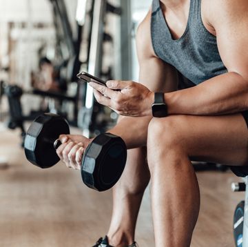 muscular young man training at gym with smart phone