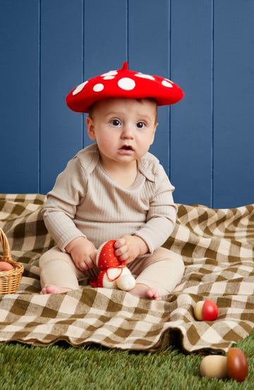 baby in mushroom costume, light brown top and bottom, red beret mushroop cap hat with white spots added