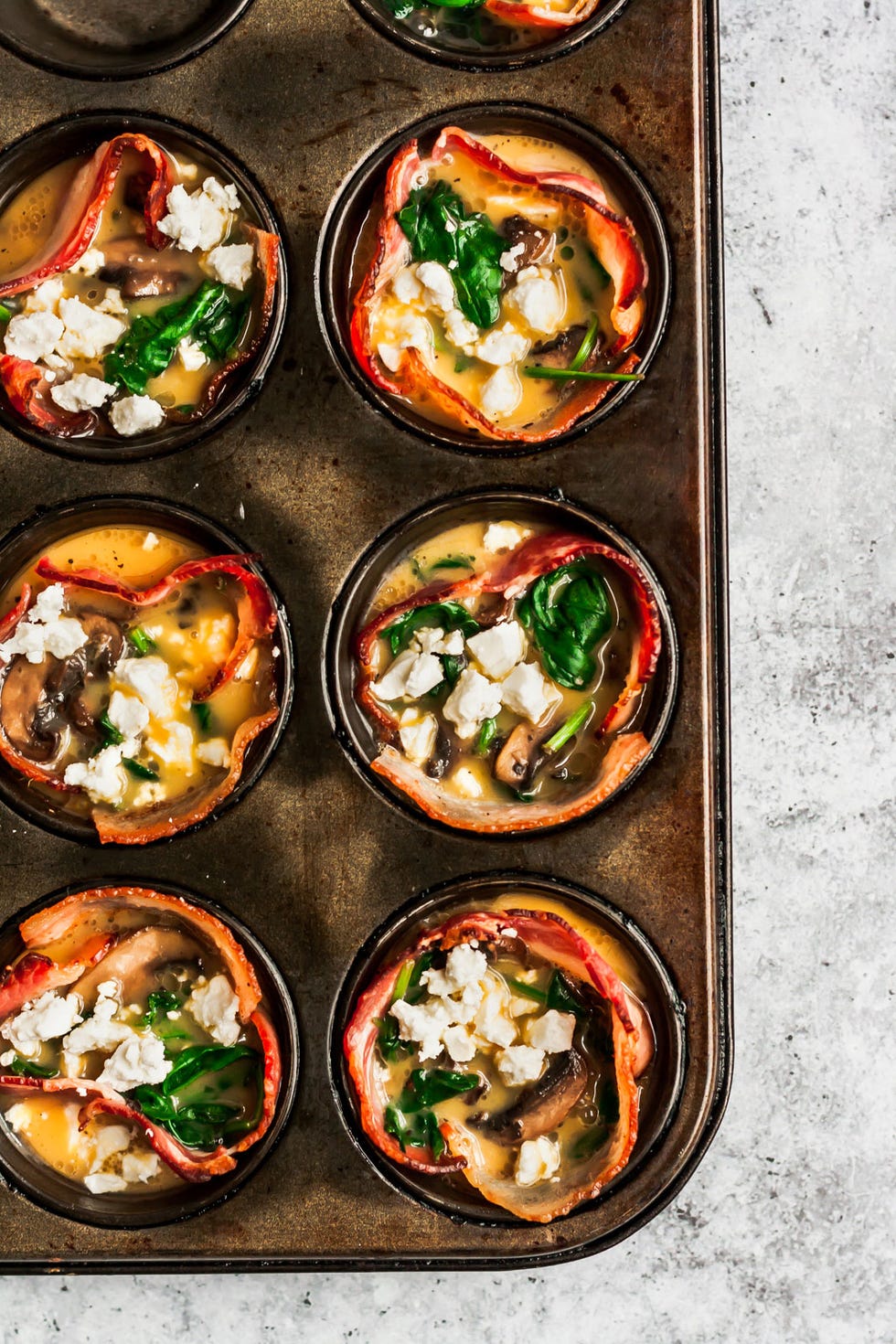 https://hips.hearstapps.com/hmg-prod/images/mushroom-spinach-bacon-egg-cups-feta-2-1563479253.jpg?crop=0.999687597625742xw:1xh;center,top&resize=980:*