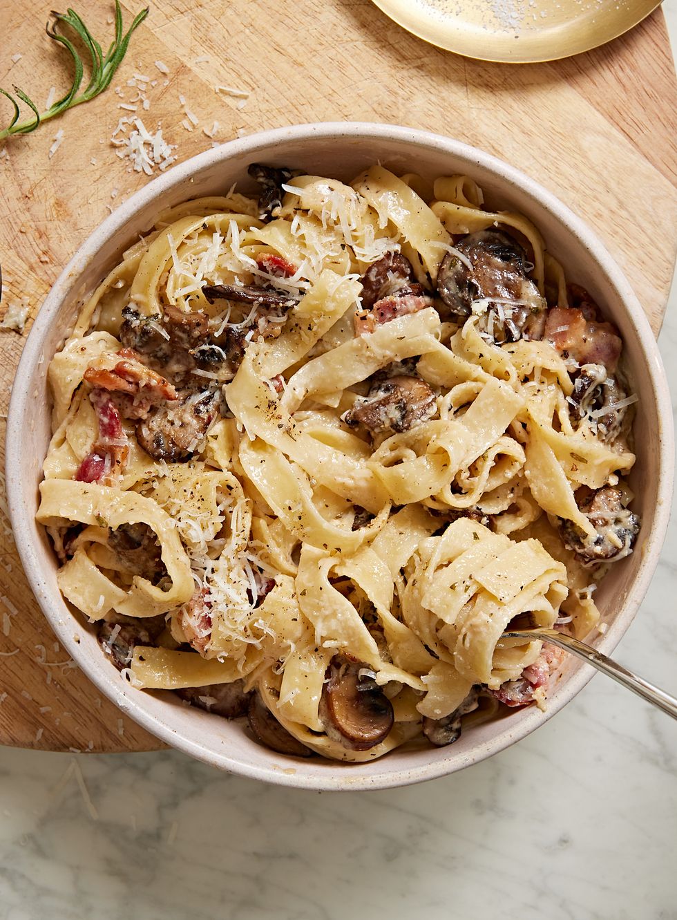 mushroom and bacon tagliatelle pasta topped with parmesan in a white bowl
