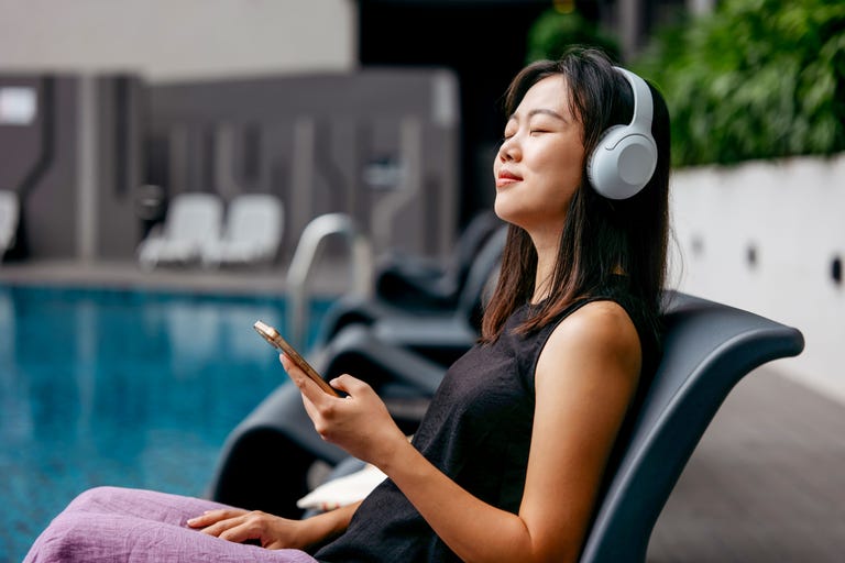 individual relaxing by a pool while listening to music on headphones