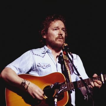 gordon lightfoot plays acoustic guitar and sings into a microphone