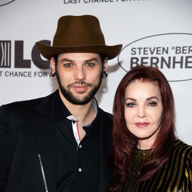 navarone garibaldi and priscilla presley smiling for a photo in front of an event backdrop