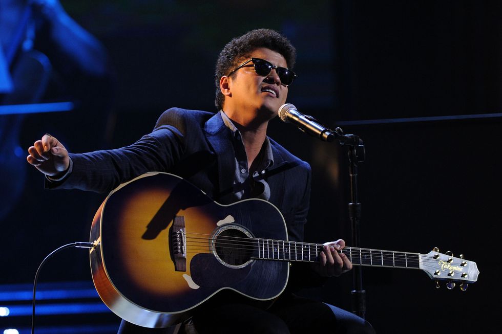 bruno mars performs onstage with guitar
