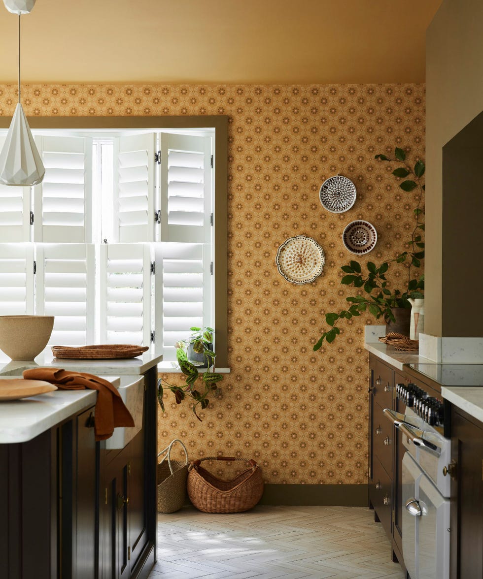 Colourful kitchen with mustard-coloured wallpaper and painted ceiling