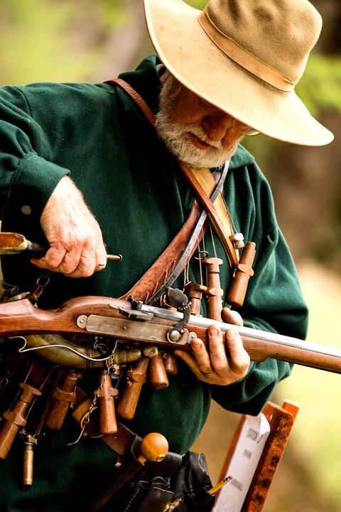 Steve Alford adds powder to the pan of his rifle, an older matchlock style, which uses a burning rope to light the gunpowder.