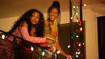 two women on a balcony decorated with string lights