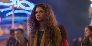 zendaya shooting a scene for euphoria she's standing in a carnival, and you can see the lights of the carnival rides behind her