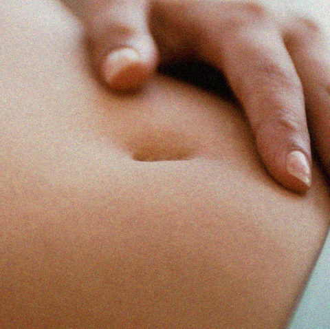 woman rests her hand on her stomach