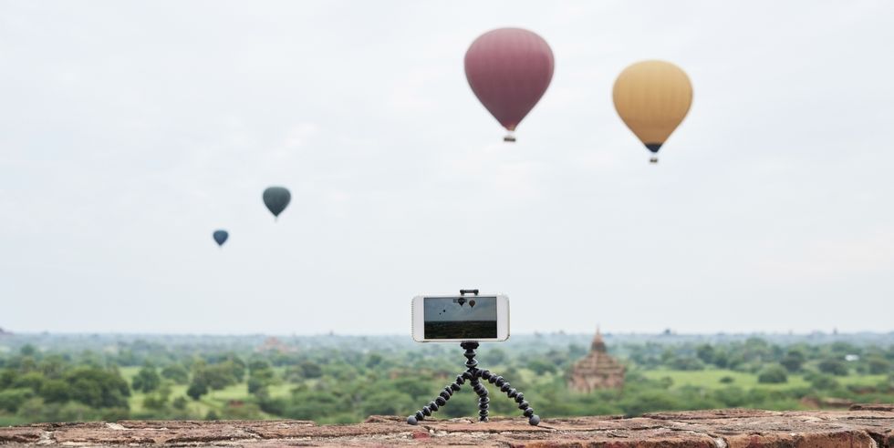 Myanmar, smartphone taking a time lapse of many hot air balloons flying over Bagan