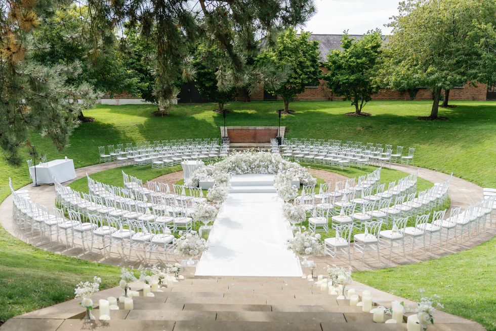 a large white fountain surrounded by white chairs and trees