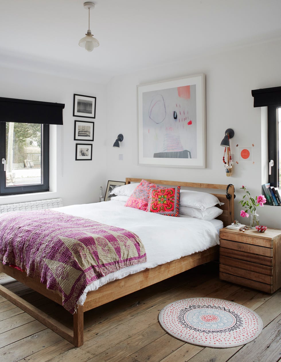 wooden bed and small drawer unit in a white walled room