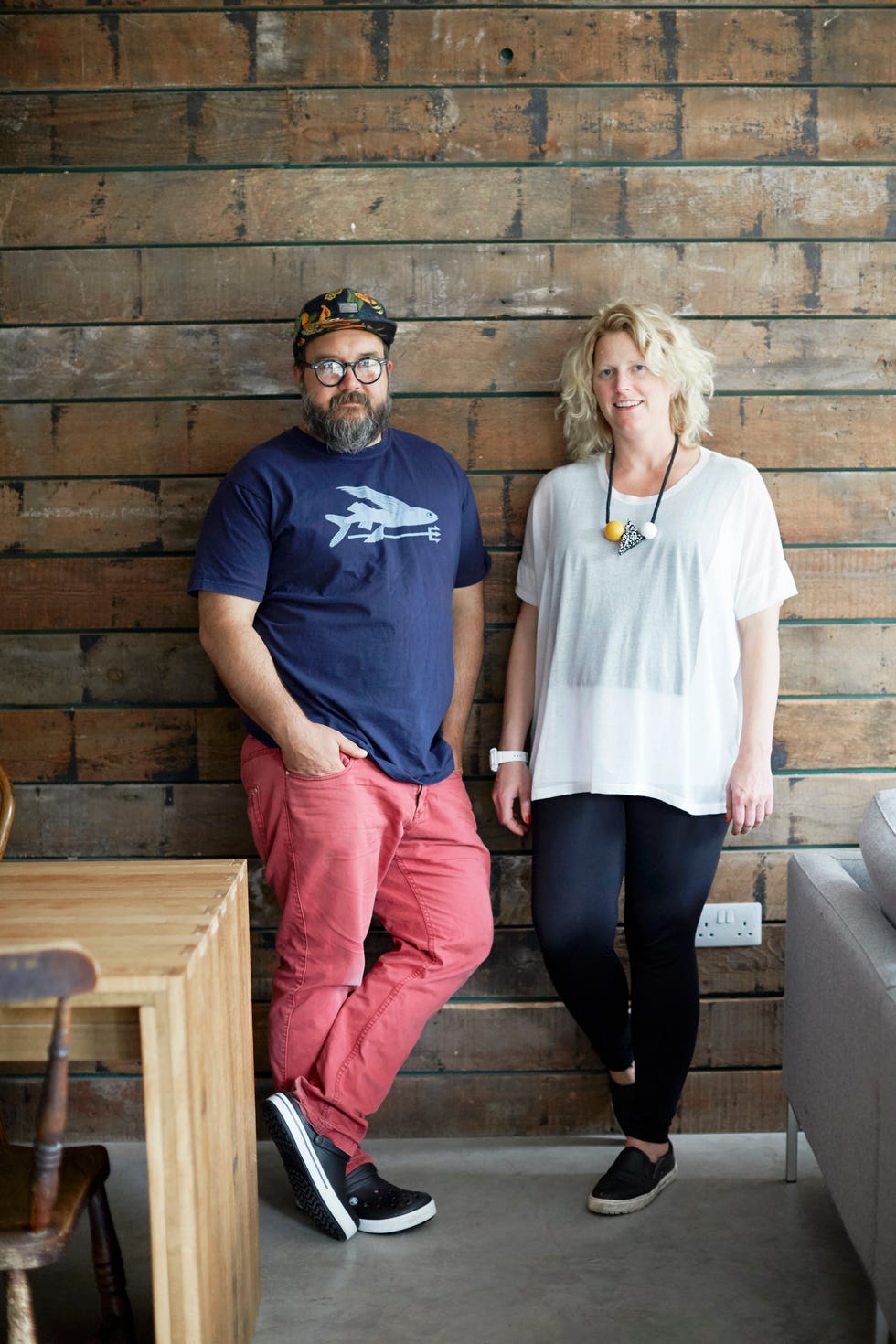 a couple leaning against a timber clad wall