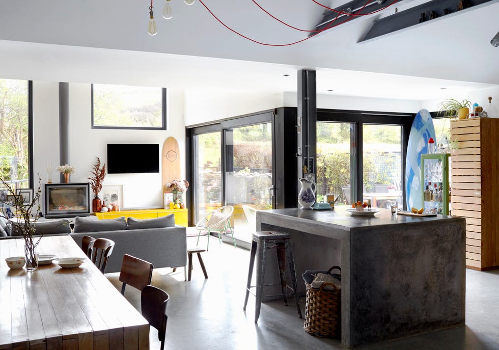 open plan kitchen, living and dining area, with contemporary island fashioned from poured concrete and sleek woodburner