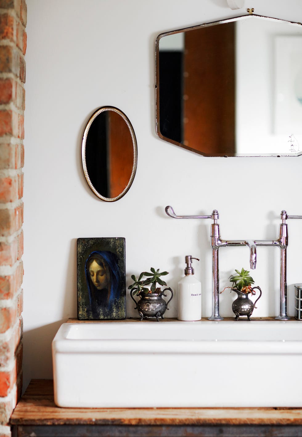 a collection of old mirrors line the wall above the reclaimed hospital sink