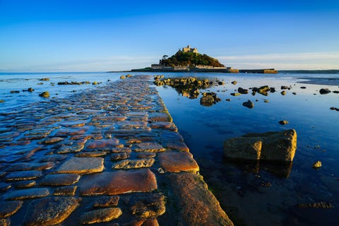 Evenals zijn Franse tegenhanger deMontSaintMichel werd dit getijdeneilandje voor de kust van Cornwallin de elfde eeuw geschonken aan de benedictijner orde van MontSaintMichel hoewel de eerste bouwwerken op het eilandje pas uit de twaalfde eeuw stammen Bij laagtij kunnen bezoekers vanuit het oude vissersplaatsje Marazion over een met keitjes geplaveid looppad naar het eilandje lopen Bij hoogtij nemen ze een motorbootje vanuit het haventje