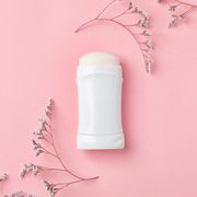 white deodorant and herbs on color background