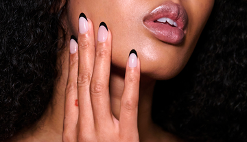 a closeup of a woman showcasing stylish blacktipped nude nails and a natural lip color