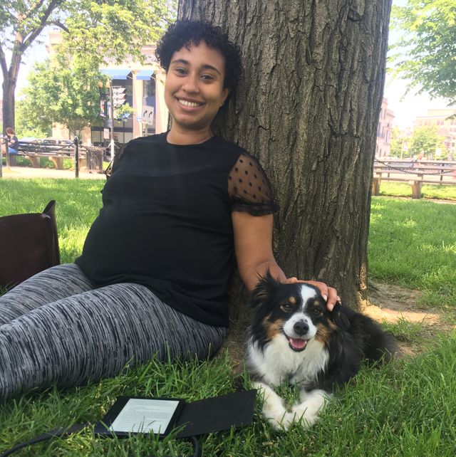 naima coster, who is pregnant, sits against a tree with her dog