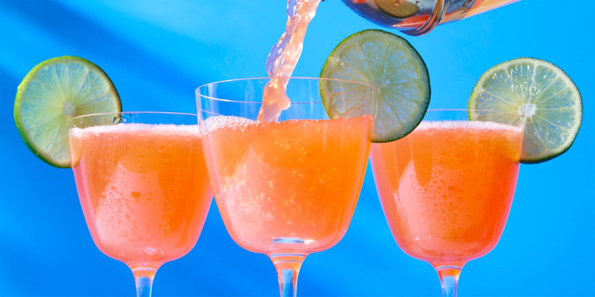 three colorful cocktails with lime garnishes on a vibrant background
