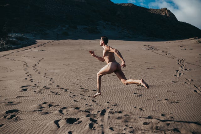 naked man running through the desert dunes