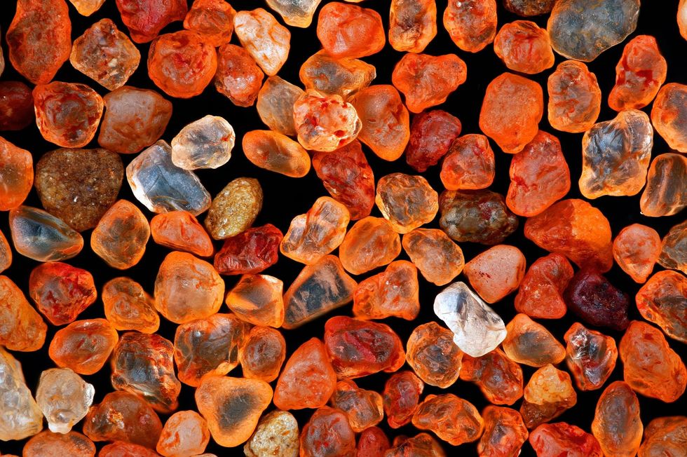 Deze opgloeiende stenen lijken misschien wel op de infinity stones uit het fictieve Marvel Universe maar het zijn in feite korreltjes zand die tien keer zijn vergroot op een foto van fotograaf Xinpei Zhang Het zand uit de Namibwoestijn in het zuiden van Afrika dankt zijn felle kleur aan de aanwezigheid van een grote hoeveelheid ijzer