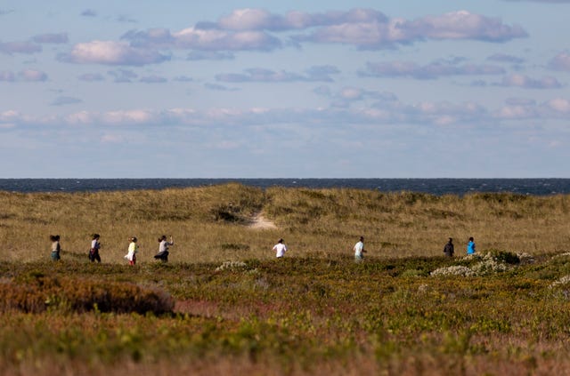 a group of people running in a grassy area near the ocean